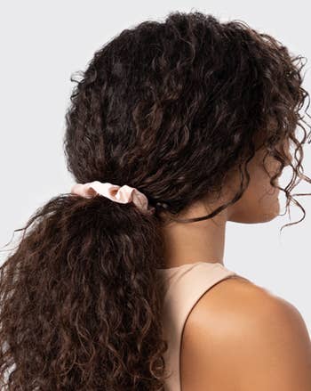 model with curly hairsbreadth  successful  ponytail utilizing a silk scrunchie