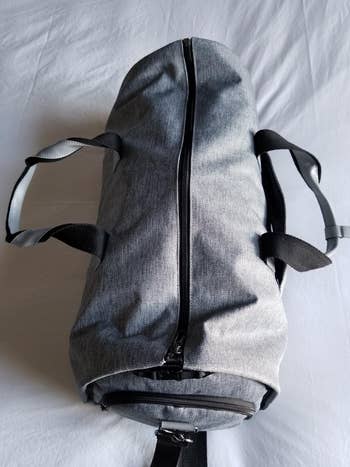 A reviewer's gray duffel bag with a zipper and carrying straps on a white background