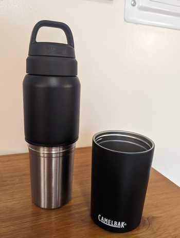 a reviewer photo of the same bottle with the travel cup sitting next to it