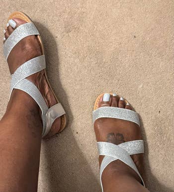 Person wearing sparkly strappy sandals, lasting  connected  a carpeted floor