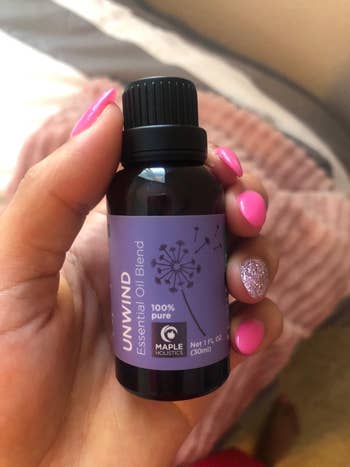 a reviewer holding the purple unwind bottle