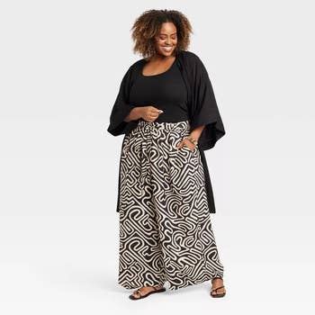 model in a black top and abstract patterned wide leg pants