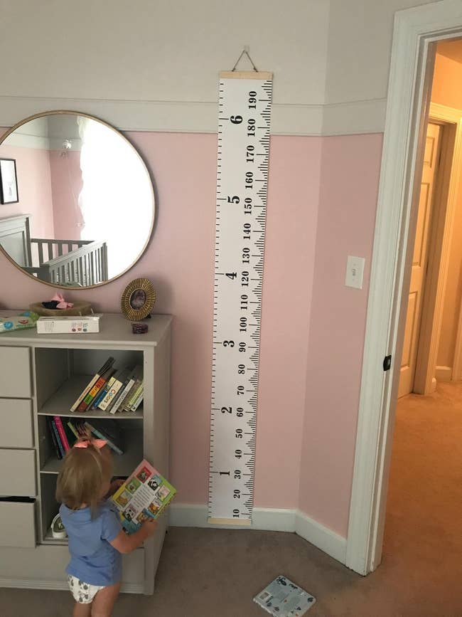 reviewer's toddler standing near a six foot growth chart on a pink wall