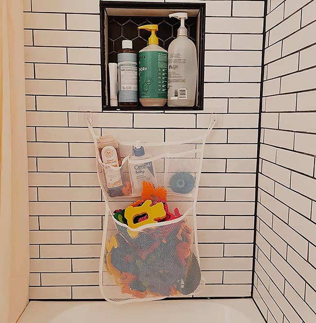 reviewer's mesh pockets filled with toys attached to a bathroom wall