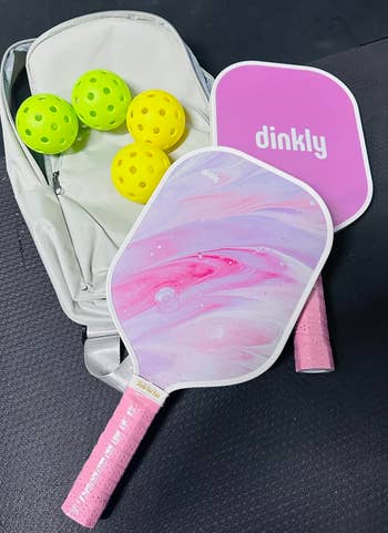 two paddles successful a marble pinkish plan adjacent to 4 balls and a carrying bag