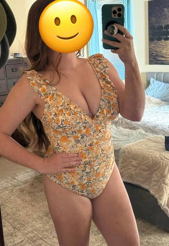 Person successful  a floral one-piece swimsuit with ruffled straps takes a reflector  selfie successful  a chamber  setting