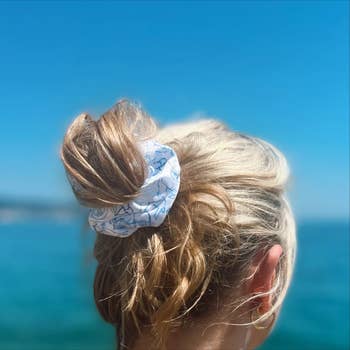 Model wearing a blue and white scrunchie with Harry Styles-themed patterns 