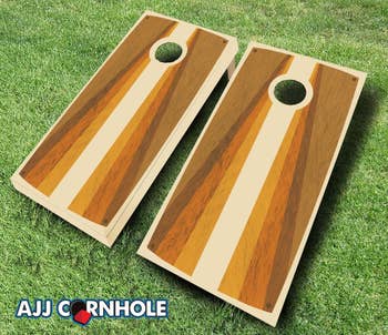 Two identical retro woody  painted cornhole sets connected  grass