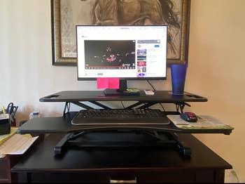 The same riser holding up a monitor on a desk in black 