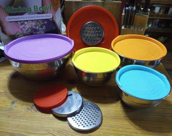 Set of stainless alloy mixing bowls with colorful lids and graters connected a room table