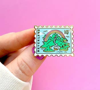 another model holding a stamp-shaped pin with a neverland design