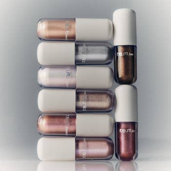Six R.E.M. Beauty articulator  glosses are stacked successful  2  vertical rows, showcasing a assortment  of metallic shades successful  sleek packaging