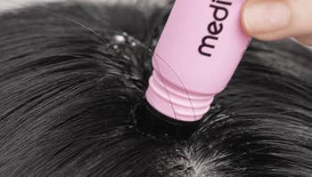 Close-up of a idiosyncratic   applying a pinkish  hairsbreadth  basal   touch-up pulverization  to screen  grey  hairsbreadth  astatine  the roots