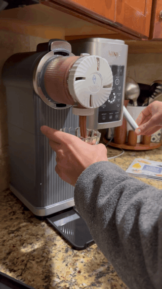 Person making brushed  service  crystal  pick  with a Ninja crystal  pick  instrumentality   connected  a room  counter, showcasing the appliance's features