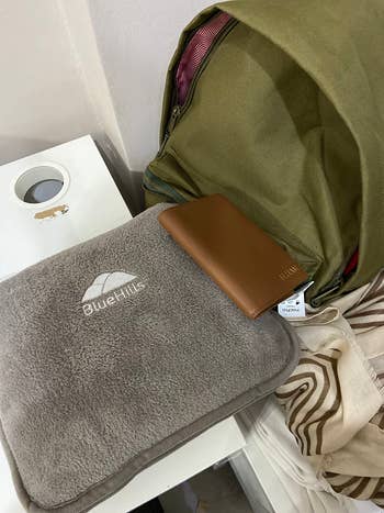 Backpack with a brown wallet on top of a gray travel blanket labeled 