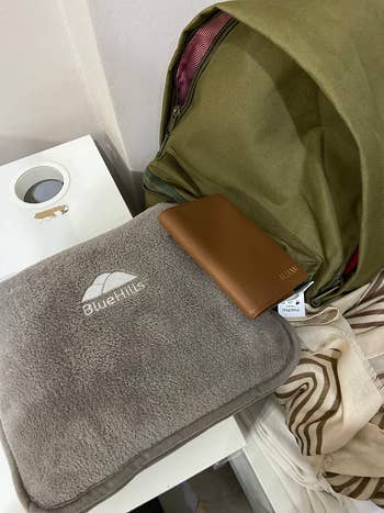 Backpack with a brown wallet on top of a gray travel blanket labeled