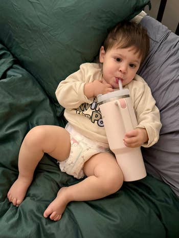 a toddler drinkning from a rose quartz stanley tumbler