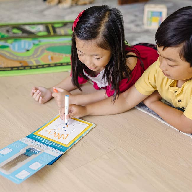 two kids drawing on a wipe off activity pad