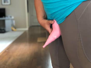 a clothed reviewer holding the urination device to their pubic area