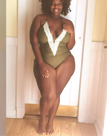 Reviewer wearing the olive plunging one-piece with strappy details across the chest and white crochet