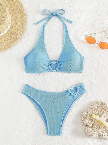 Blue bikini with heart detail on top and bottom, displayed flat with accessories