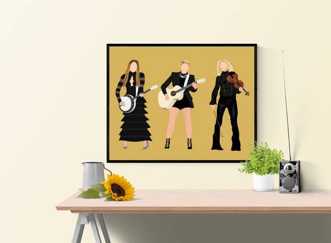 art print of the Dixie Chicks illustrated with their instruments on a yellow background 