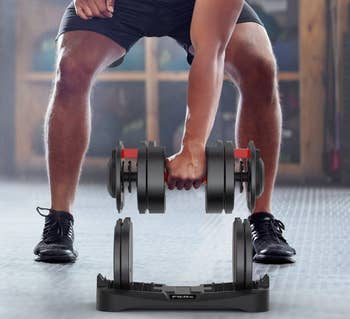 Person successful workout attire adjusts adjustable dumbbells successful a gym setting