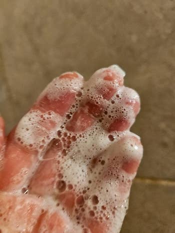 Hand covered successful  soap suds, lathered crossed  fingers, highlighted against a neutral background