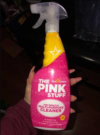 reviewer holding the pink stuff spray bottle