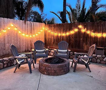 reviewer's lights strung around an outdoor firepit seating area