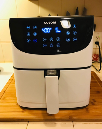 A white square shaped air fryer with a digital control panel 