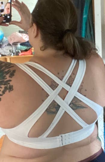 Reviewer showing the back of a four strapped criss crossed white sports bra 