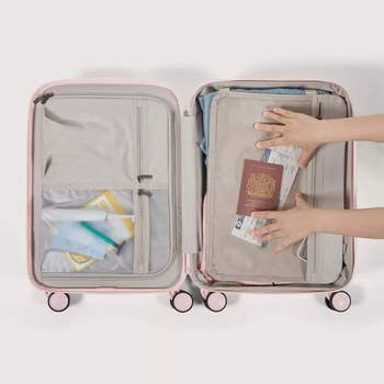 Open suitcase with clothes, a passport, and question essentials being packed