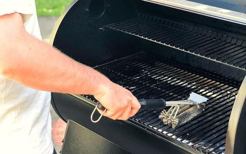 a reviewer using the brush to clean a grill grate