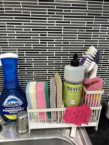 Kitchen descend with assorted cleaning supplies, including sponges, scrub brushes, and soap bottles organized successful a caddy