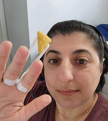 reviewer wearing the white finger chopsticks, which are holding a chip