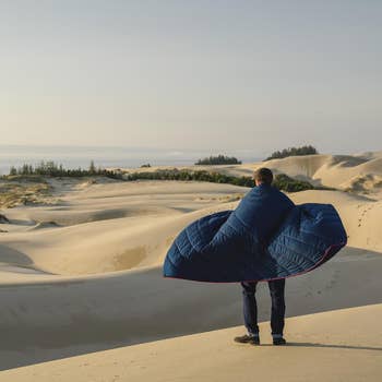 model wearing blue puffy blanket in front of sand dunes