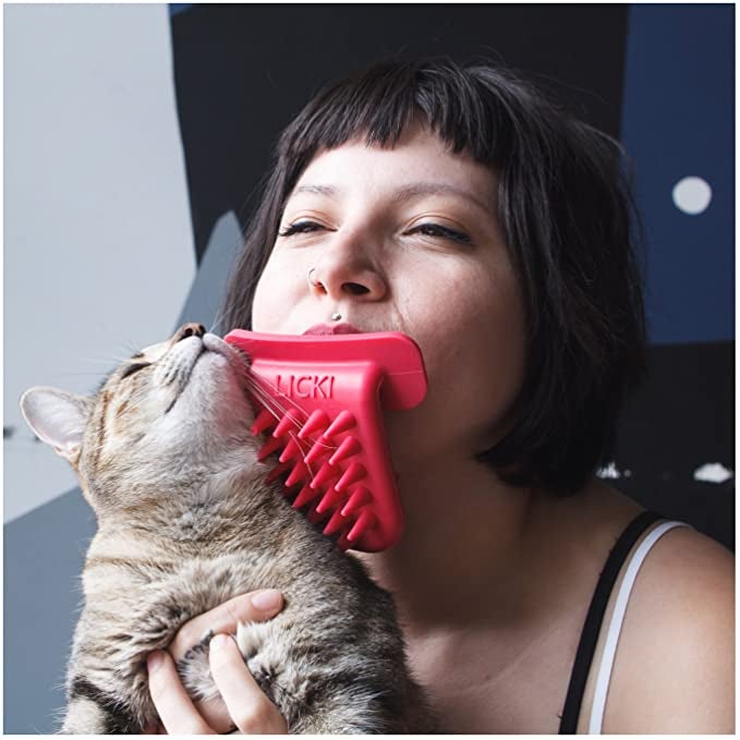 model with the red Licki in their mouth, using it to brush their cat