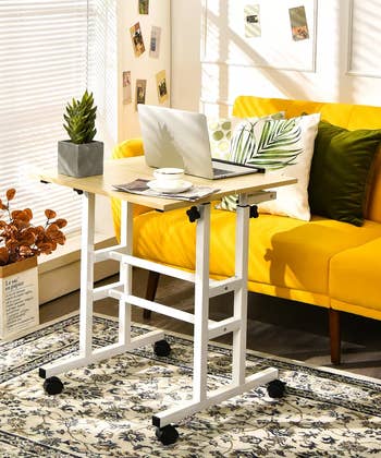 Adjustable standing desk with wheels next to a couch