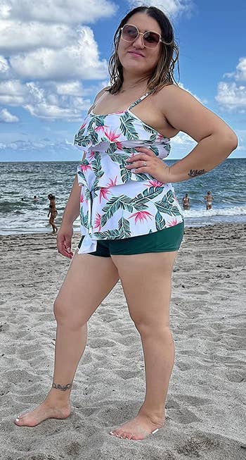 a reviewer wearing a white ruffle top with a palm print with matching dark green shorts 