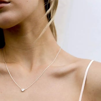 a model wearing a silver heart necklace
