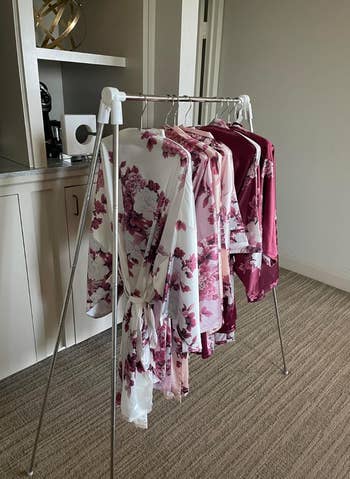 A clothing rack with various floral robes hung from it 