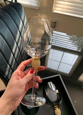 reviewer holding wine glass with gold rhinestones on the stem and a gold rim
