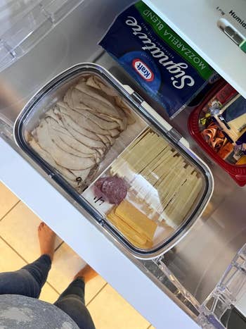 Sliced turkey, cheese, and salami are neatly arranged successful  a fridge drawer, with packaged mozzarella food  and chocolates nearby