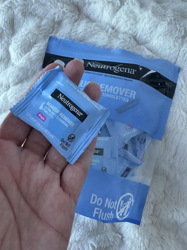 Hand holding a Neutrogena constitution remover wipe, with a container of further wipes successful the background