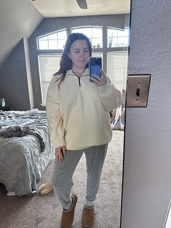 reviewer taking a picture in the mirror wearing the apricot pullover