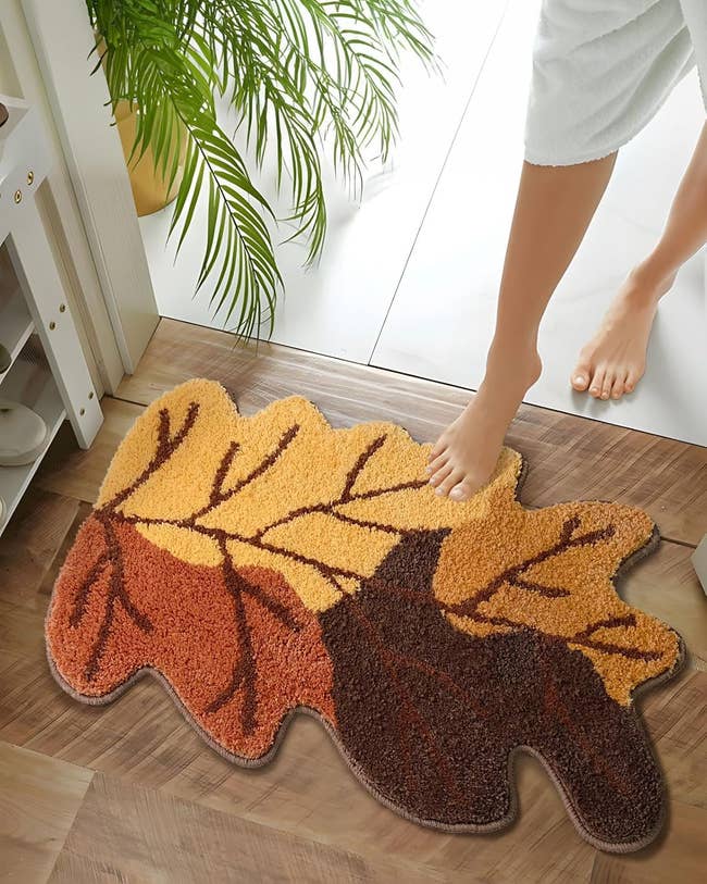 A idiosyncratic steps onto a leaf-shaped bath mat with a leafage design, successful a location mounting adjacent a plant. This representation is utilized successful an nonfiction astir buying for location decor