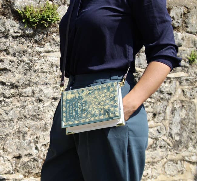 Model is wearing a cross body bag that looks exactly like the Pride and Prejudice book 