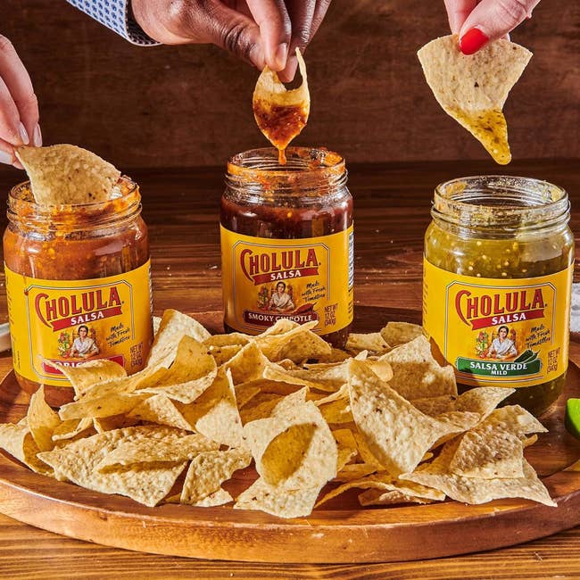 three jars of salsa with chips being dipped into each jar