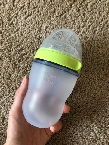 reviewer holding the bottle with green lid and clear cap